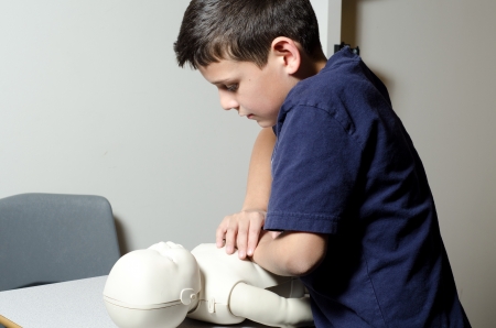 A 9 years old child practing CPR on a dummy 