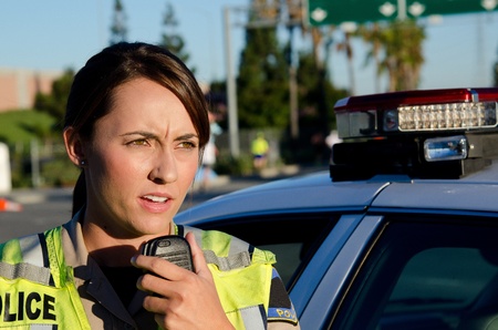 a female police officer standing next to her vehicle as she talks on the radio の写真素材