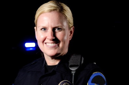 a smiling female police officer in the night during her shift  