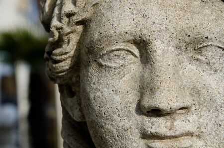 A close up of a statue of a woman's face at a garden.