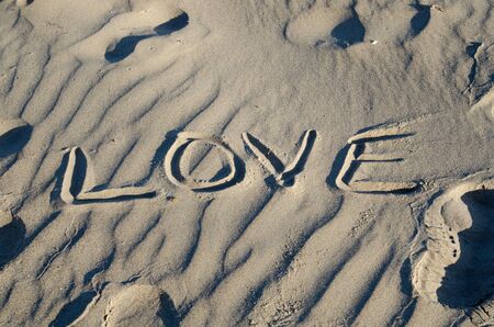 The word love spelled out in the sand in the morning.の写真素材