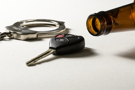 A beer bottle on its side with handcuff and car key 