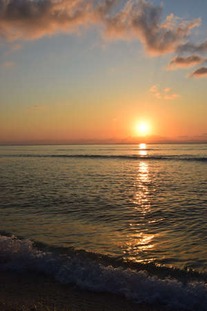 Golden reflection of sunset on the shore of a calm ocean