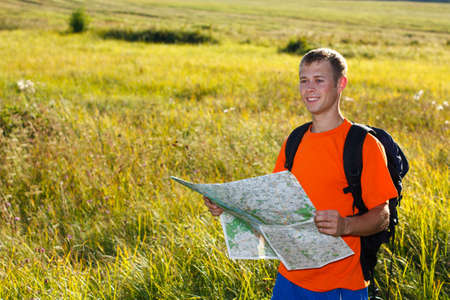 Man traveler with read the map and smiles against a background of green nature