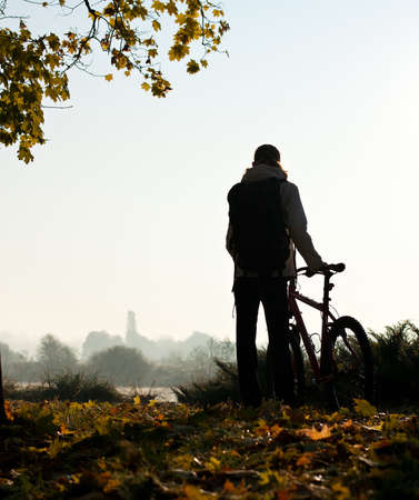 Silhouette of woman with bicycle with beautiful nature by the break of dayの写真素材