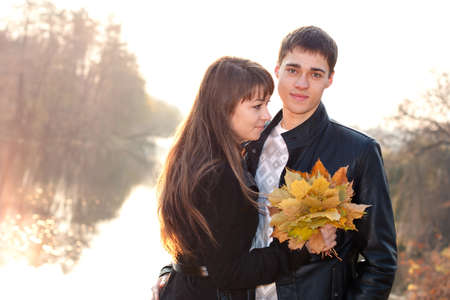 Young beautiful happy smiling couple in love against the background of backlit beauti autumn natureの写真素材