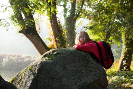 Young hiker woman enjoying relaxation in rocks among the green humid nature in the foggy sunny morningの写真素材