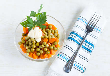 Vegetarian salad with canned green peas, boiled carrots, mayonnaise and fork  Top viewの写真素材