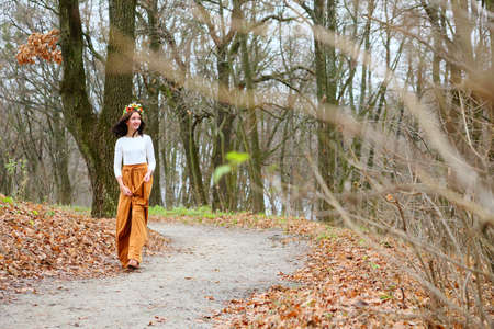 Young beautiful girl with flower wreath outdoors in the autumn forest. Beauty concept