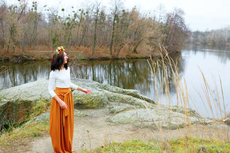 Young girl with flower wreath outdoors near the river. Beauty autumn concept