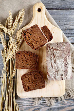 Slices of rye Bread with spikelets of wheat on a cutting board. Top view