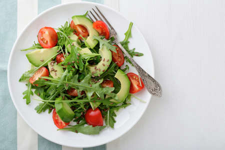 Fresh Avocado Salad with cherry tomatoes and arugula on a stripy background. Top viewの写真素材
