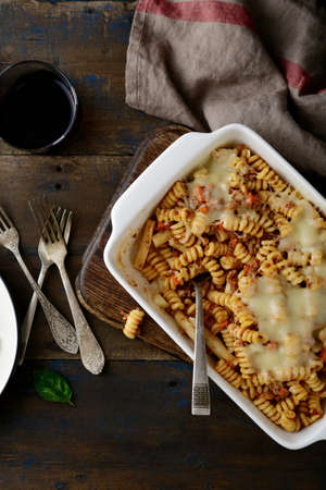 Pasta with a Bolognese beef sauce in baking dish and wine on a wooden background. Top viewの写真素材