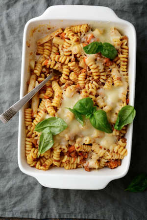 Pasta Bolognese, cheese and basil in white baking dish on a linen napkin. Top viewの写真素材