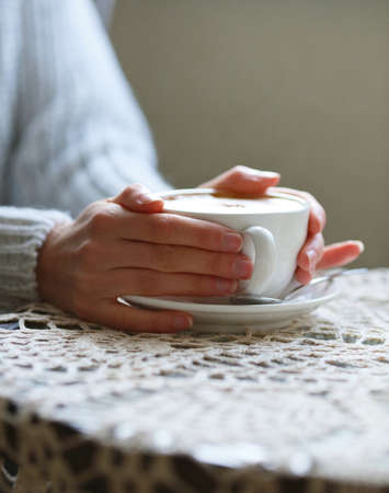 Cup of cofee in female hands on table closeup. Cafeの写真素材