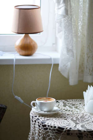 Cup of coffee on a table near a window in cafeの写真素材