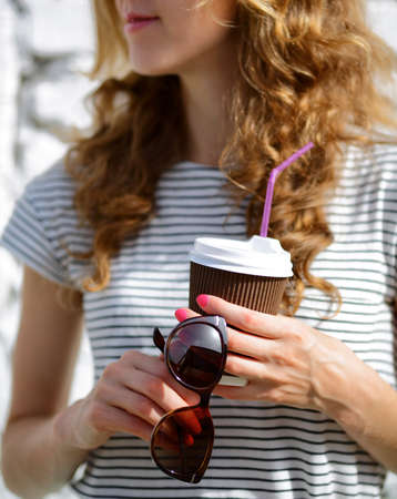Sunglasses and Disposable Coffee Cup in the woman hands. Morning drinksの写真素材