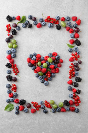 Mixed berries shaped as a heart and frame on slate backgroundの写真素材