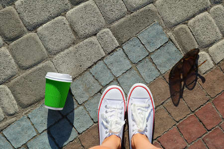White gumshoes, disposable cup and sunglasses on the background pavement. Hipster styleの写真素材