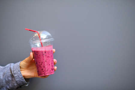 Disposable cup with a Smoothies in woman hand on gray backgroundの写真素材