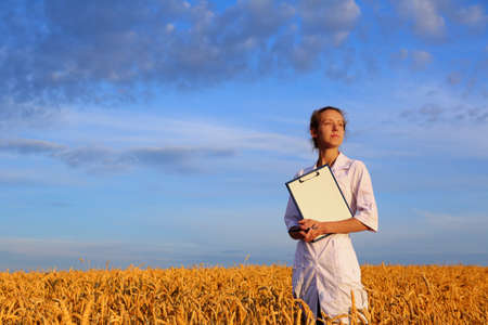 Agronomist or a student or a scientist with document in hand against the background of a golden...