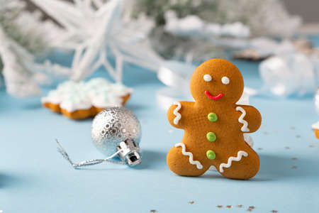 Christmas gingerbread cookies with silver Christmas decorations on blue surface