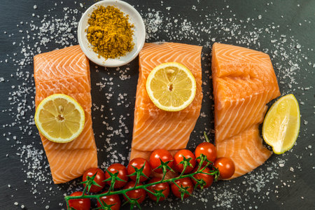 Top view of fresh raw salmon fish steak with spices on a dark stone background. Salt, spices, seasonings and other ingredients.の写真素材