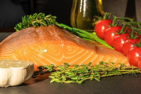 Top view of fresh raw salmon fish steak with spices on a dark stone background. Salt, spices, seasonings and other ingredients.の写真素材