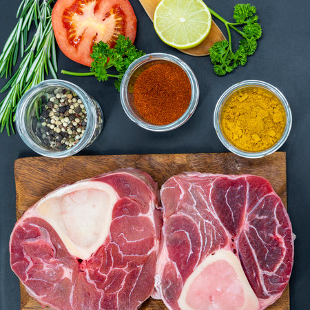 Fresh raw beef steaks ready for grilling, shot from above. Seasonings, vegetables, fruits and herbs.の写真素材
