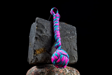 Braided paracord keychain on a background of stones. Handmade, creative design.の写真素材