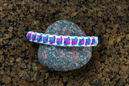 Braided paracord bracelet on the background of stones. Handmade, creative design.の写真素材
