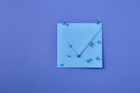 Beautiful forget-me-not flowers with kraft blue envelope on blue background with space for text. Happy Mother's Day, St. Valentine's day greeting card. flat lay.の写真素材