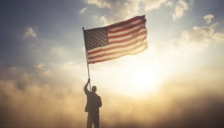Businessman holding american flag against blue sky over clouds with sunの素材