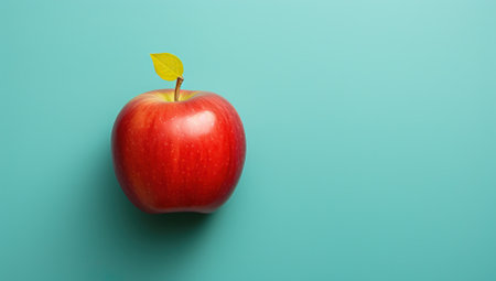 Vibrant red apple on a turquoise background, concept of healthy eating and nutritionの素材