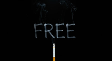 The word FREE spelled out in smoke from a cigarette, against a black background, symbolizing concepts like freedom from addiction or the cost of smoking.の素材