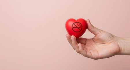Hand holding a red heart with a no smoking symbol. Concept for quit smoking, heart health, and healthy lifestyle.の素材