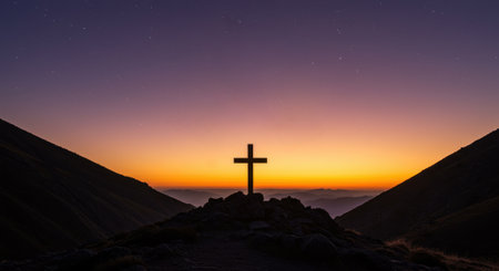 Christian cross silhouette on a hill at dawn, set against a colorful sky and framed by dark mountains. Symbol of faith, hope, and religion.の素材