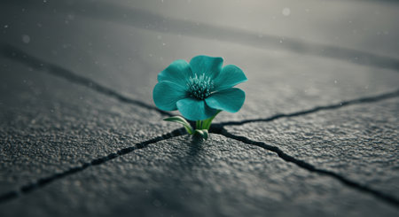 Teal flower growing through cracked concrete surface, symbolizing resilience, determination, and overcoming adversity in challenging environments.の素材