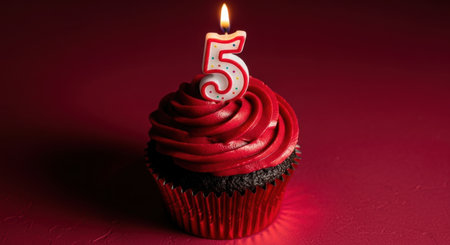 A delicious red velvet cupcake with vibrant red frosting and a lit number 5 candle, symbolizing a fifth birthday or anniversary celebration.の素材