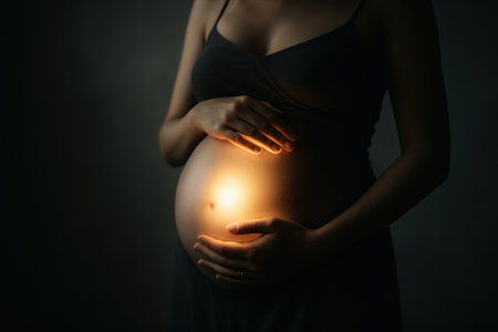 Pregnant woman belly illuminated by a warm, radiant glow, hands gently cradling her unborn child. Symbolizing new life, hope, and the miracle of motherhood.の素材