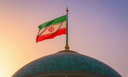 Iranian national flag with green, white, and red stripes waving on a mosque dome against a vibrant sunset sky. symbolizes nation, government, and culture.の素材
