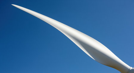 Leading edge of a pristine white wind turbine blade against a clear blue sky, symbolizing clean energy, sustainability, and green technology.の素材