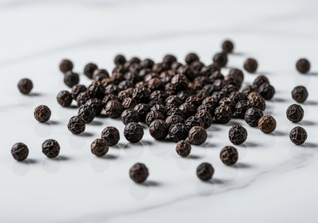 Black peppercorns, a common spice, scattered on a light surface. essential ingredient for cooking, adding flavor and aroma to various dishes.の素材