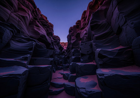 Narrow desert canyon with smooth, flowing basalt rock formations under a deep twilight sky. reddish sand covers the ground, creating an otherworldly, mysterious landscape.の素材