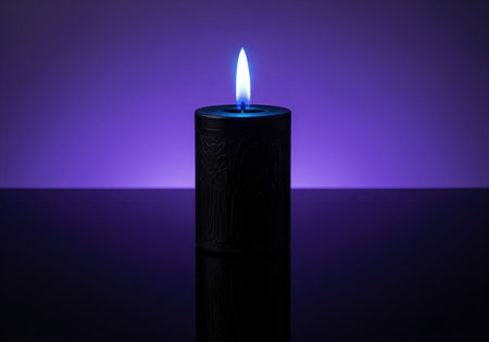 A single black candle with a bright electric blue flame stands on a dark reflective surface, illuminated by a vibrant purple background, creating a mystical and atmospheric scene.の素材