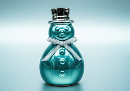 Teal glossy ceramic snowman figurine wearing a silver top hat and a decorative ribbon. reflective surface on a light blue background, perfect for winter and holiday themes.の素材