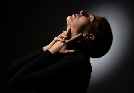 Woman with head tilted back and eyes closed, hands touching her neck, conveying intense emotion, pain, or distress. ideal for themes of struggle or discomfort.の素材
