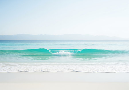 Clean turquoise ocean wave breaking gently onto a bright white sandy beach under a clear, bright sky. tranquil tropical seascape ideal for relaxation and travel themes.の素材