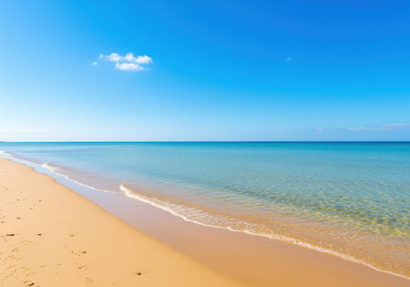 Pristine golden sand beach stretching along the coastline, meeting the clear, shallow turquoise ocean water under a vast, bright blue sky with a single cloud. perfect tropical paradise background.の素材