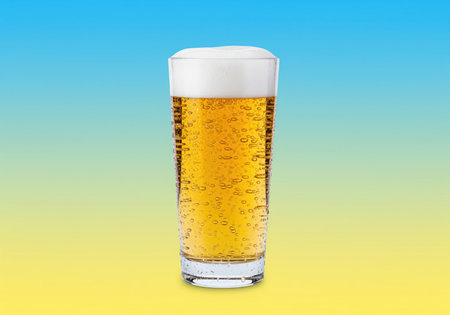 Cold lager beer in a tall glass featuring a thick white foam head, condensation, and numerous rising bubbles. the golden beverage is set against a vibrant blue and yellow gradient background, emphasizing refreshment and summer.の素材